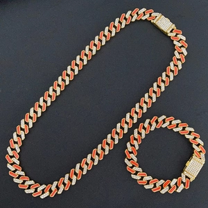 Detail of hip hop Cuban link chain set with orange enamel and sparkling rhinestones