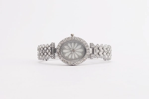 Macro shot of silver ladies watch with crystal inlay and white floral pattern dial
