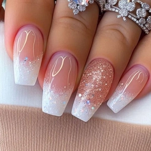 Macro detail of coffin shaped nails with white ombre and rose gold glitter accents