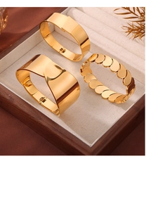 Close-up of three 18k gold-plated stainless steel bangles in a luxury wooden jewelry box