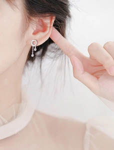 Close-up of long silver tassel drop earrings with circle and waterdrop charms on model