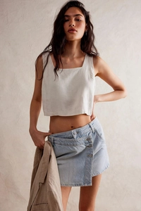 Détail d'une jupe en jean irrégulière bleu clair avec un blazer beige et un haut blanc