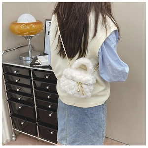 Close-up of white faux fur quilted crossbody bag featuring a delicate gold chain strap