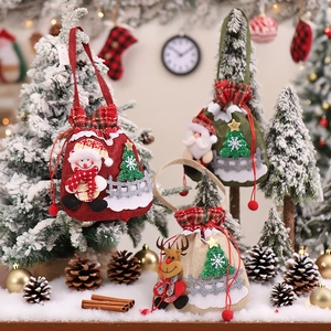 Three Christmas burlap drawstring gift bags with plush dolls on snowy festive background