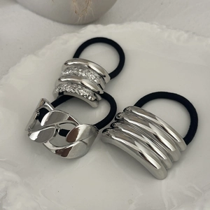 Close-up of three minimalist silver metal hair ties on an embossed ceramic tray