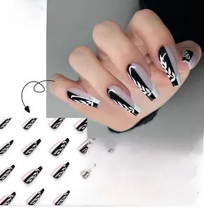 Detail of French tip press-on nails with black and white leaf art in coffin shape