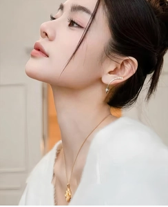 Detailed view of elegant gold-tone star pendant earring and matching ear cuff on a model