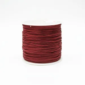 Macro shot of 0.8mm burgundy jewelry cord wound on a spool for DIY braiding crafts