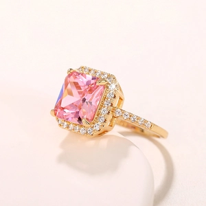Close-up of golden ring with large pink square gemstone and small accent stones