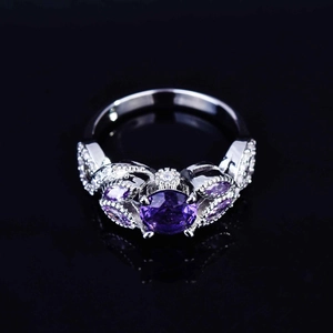 Macro shot of silver ring with round purple amethyst center and floral zircon accents