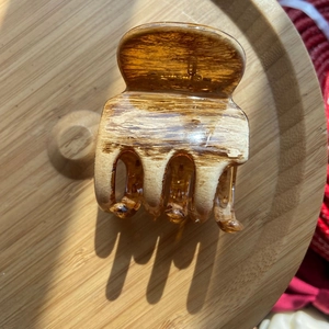 Close-up of a 13cm amber oil painting style hair claw clip on a light wooden tray