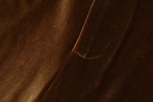 Detailed close-up of premium velvet fabric with precise stitching on brown velvet blazer