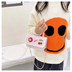 Pink tweed crossbody bag with pearl handle and floral charm shown on a child model