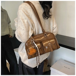 Brown vintage pillow bag with dual front buckle pockets and plush bear charm detail