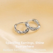 Detail of silver geometric hoop earrings with textured finish on warm yellow fabric