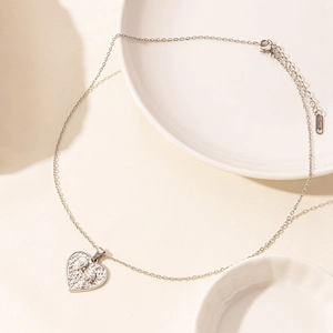 Detail of silver heart pendant with gothic relief on polished stainless steel chain