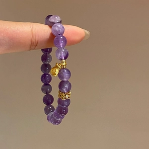 Detail of amethyst beaded bracelet with a gold money bag charm and diamond spacer