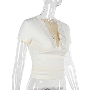 Détail du haut à col en V avec dentelle et nœud décoratif en couleur blanc crème