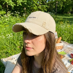 Distressed khaki baseball cap with black letter embroidery and ripped brim detailing