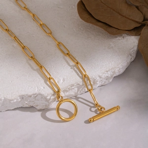 Gold paperclip chain necklace with a classic toggle clasp on a natural stone background
