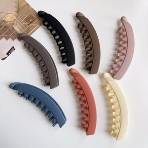 Flat lay of large matte banana hair clips in six assorted neutral colors on white background