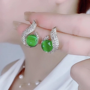 Detail of gold mermaid pearl earrings with green cat-eye stone and pavé zircon stones