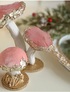 Close-up of pink velvet mushroom ornament with gold glitter and festive pine branches