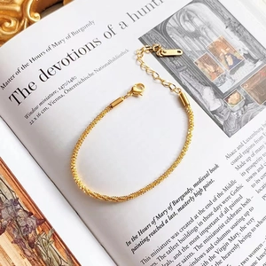 Elegant gold-tone twist chain bracelet with lobster clasp on a vintage book background