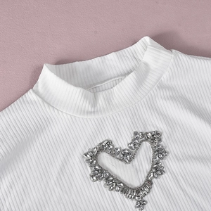 Dettaglio in maglia a coste bianca con intaglio a cuore e decorazioni in strass brillanti