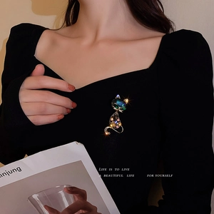 Elegant gold fox brooch with green gem and colorful crystals on a black fabric background