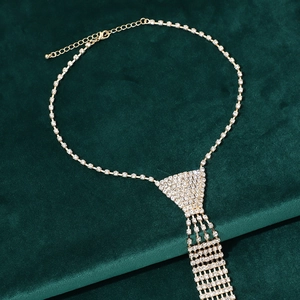 Detail of rhinestone tie necklace with gold lobster clasp and extension chain on green velvet