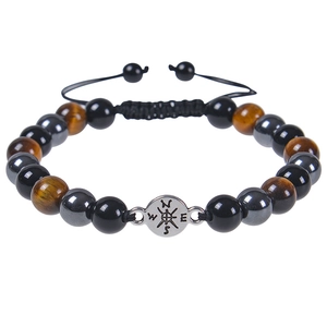 Detailed macro view of beaded bracelet with tiger eye stones and silver compass charm