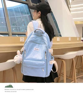 Détail d'un sac à dos bleu clair en tissu texturé avec un charmant lapin blanc