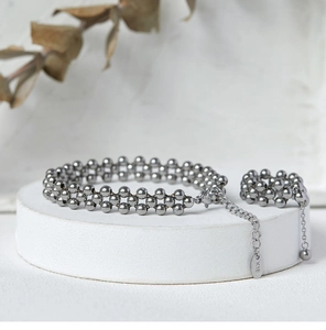 Detail of beaded bracelet and ring set with 18K gold tag on a white platform