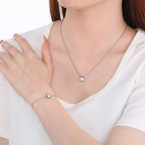 Detailed view of silver shell pearl necklace and bracelet set on model's neck and wrist