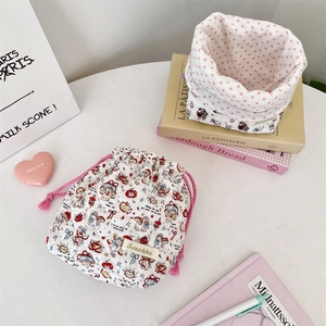 Detailed view of quilted drawstring storage bag with cartoon patterns and pink polka dot lining