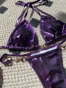 Detail of purple metallic bikini fabric with golden hardware and pearl accents