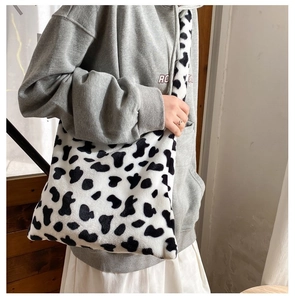 Detail of soft plush cow print tote bag showing texture and size on a female model