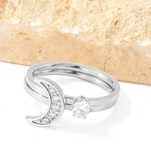 Silver crescent moon ring with white zircon stones on a natural textured stone background