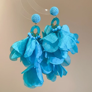 Macro shot of blue silk petal tassel earrings with beaded studs and gold metal details