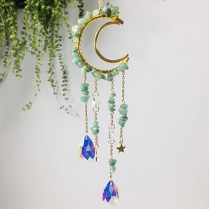 Golden moon suncatcher with amethyst stones and crystal prisms hanging by a green plant