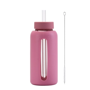 Detail of pink glass water bottle with silicone sleeve, straw, and cleaning brush