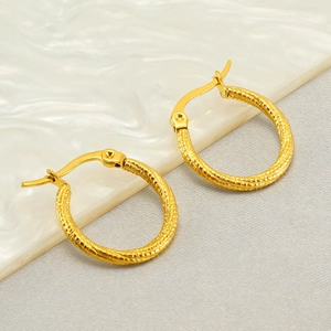 Golden stainless steel hoop earrings with woven texture on marble background
