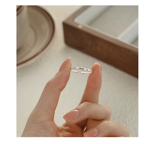 Close-up of hand holding a silver adjustable ring with colorful rainbow cubic zirconia