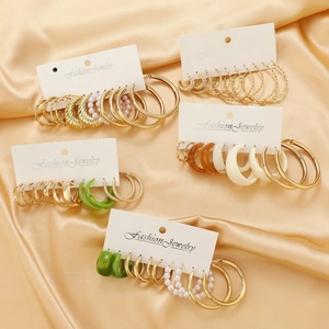 Chic gold hoop earring set with resin rings displayed on elegant gold satin fabric