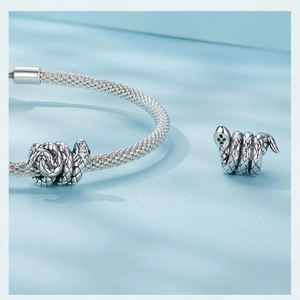 Macro shot of silver coiled snake charm with crystal eyes on a mesh metal bracelet