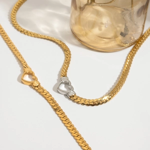 Detail of 18K gold snake chain necklace featuring a two-tone heart clasp design