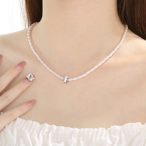 Detailed close-up of white rice-shaped glass pearls and silver girl pendant necklace