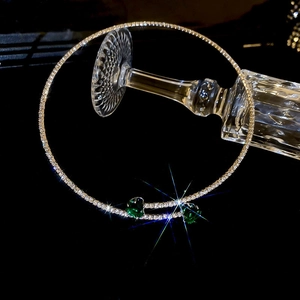 Detailed close-up of sparkling silver choker with heart-shaped green gemstones