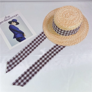 Détail d'un chapeau de paille à sommet plat avec rubans élégants à carreaux noir et blanc